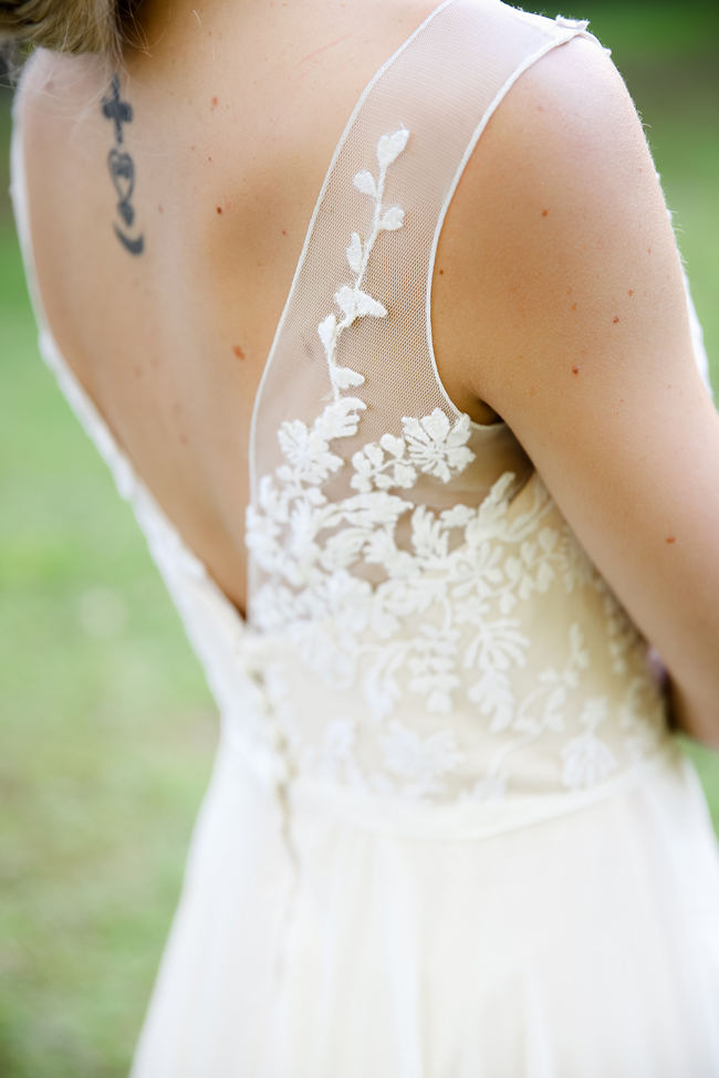 A deep V style Lace back wedding dress shows off tattoo. Lovely Rustic Garden Picnic Wedding // Nikki Meyer Photography