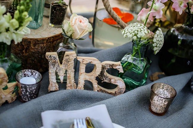 A pretty pallet picnic table using grey hessian burlap runner, filled with rustic decor elements, mercury votives, wood slabs and peach blooms in mix and match vases. Rustic Garden Picnic Wedding // Nikki Meyer Photography