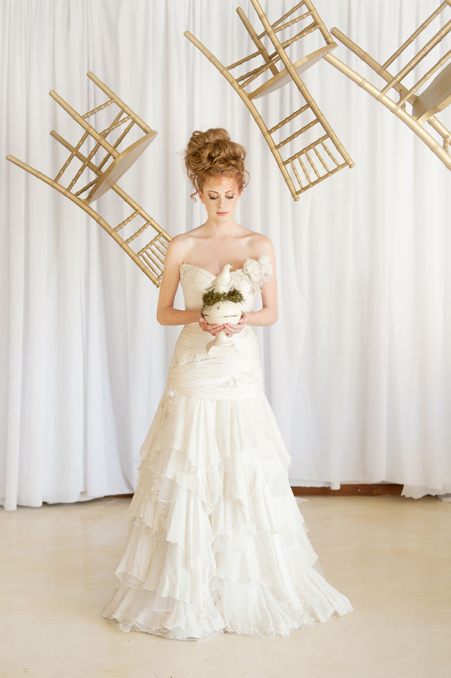 The romantic, ruffled layers of this strapless sweetheart wedding dress and messy bridal upstyle hairdo looking amazing with a backdrop of whimsically floating gold chairs.