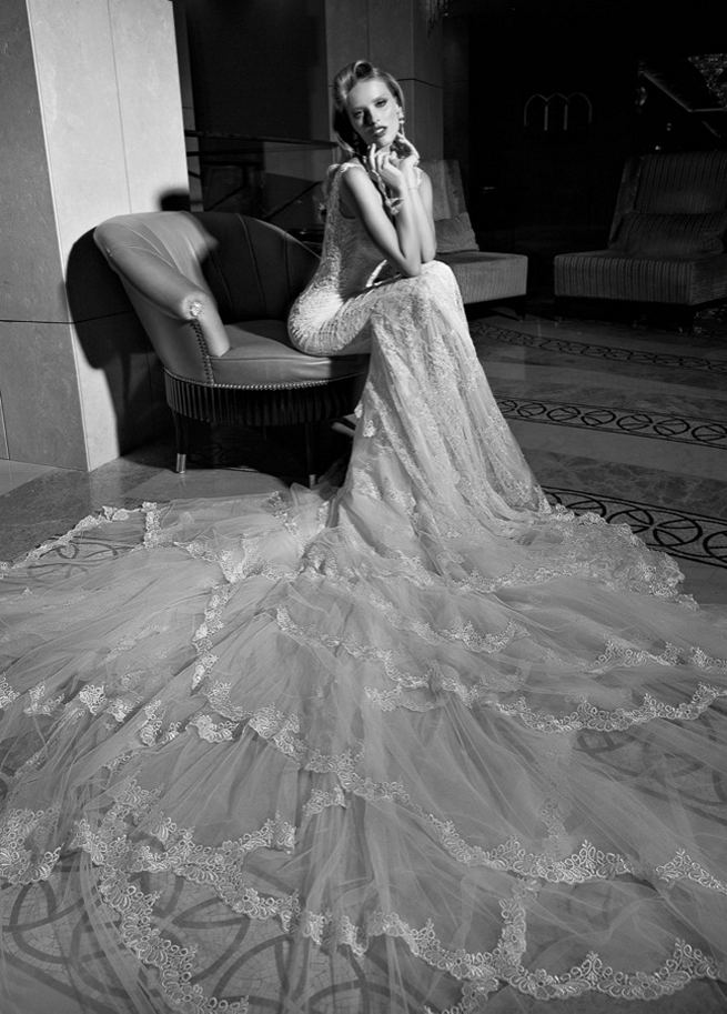 Galia Lahav's mermaid style Madison wedding dress has a colossal and dramatic train made from layers and ruffles of tulle and vintage lace. The back falls low with a heart shape. The sweetheart front is a marriage of two embroidered laces. The sides of the gown are layered with a sheer glittering fabric under an embroidered lace.