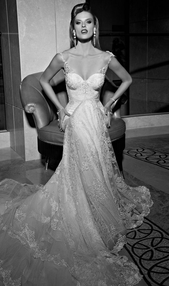 Galia Lahav's mermaid style Madison wedding dress has a colossal and dramatic train made from layers and ruffles of tulle and vintage lace. The back falls low with a heart shape. The sweetheart front is a marriage of two embroidered laces. The sides of the gown are layered with a sheer glittering fabric under an embroidered lace.