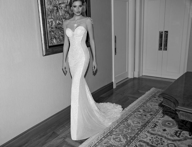 Galia Lahav's Joyce wedding dress from the 2015 Tales of the Jazz Age collection is a strapless and sheer sided art deco dress with a bejeweled top. The net fabric is fully embroidered with structural art deco motifs. The dress is finely cut with glistening sides and iridescent irregular faceted stones. The gown comes complete with a removable bejeweled necklace made of metallic mesh and crystal beaded rhodium strands.