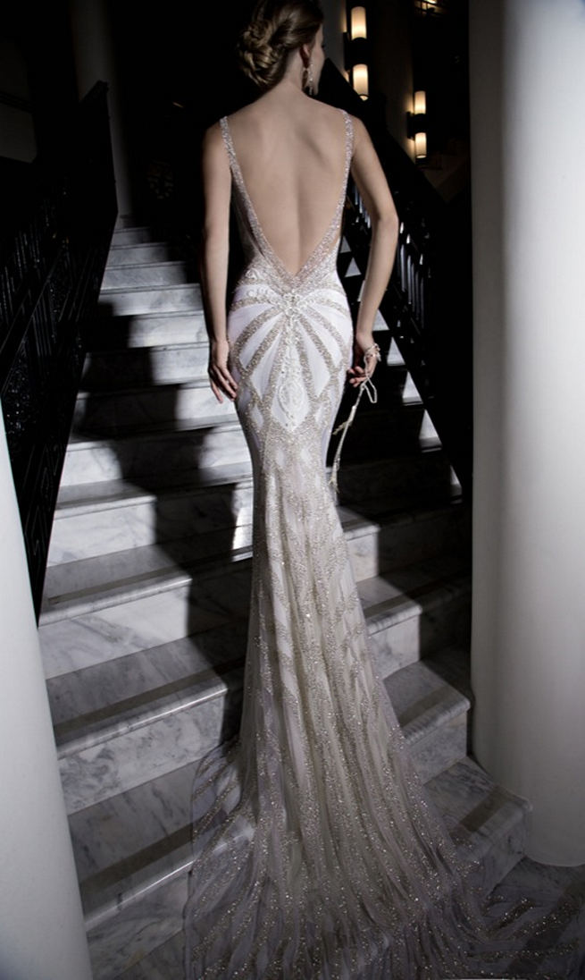 Galia Lahav's backless Katharina Wedding Dress is entirely embroidered in silver glass beads with an art deco geometric pattern. The dress has a front detail of lace paneling and a v-shaped back with graphic ivory lace details.