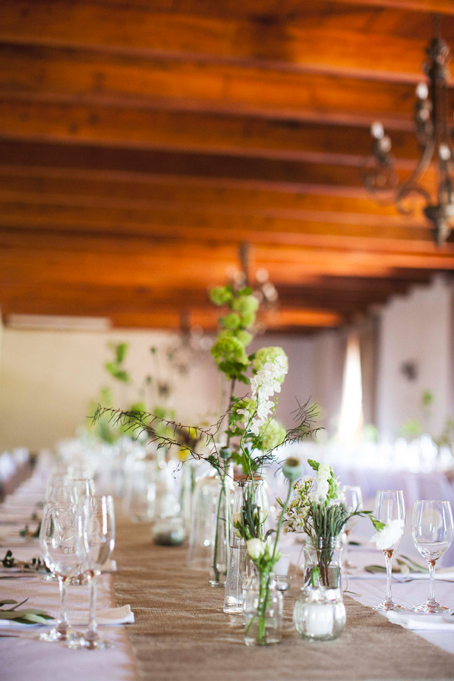 Single stem greens in mix and match bottles. Wedding reception decor. Green White Rustic South African Wedding // Justin Davis Photography