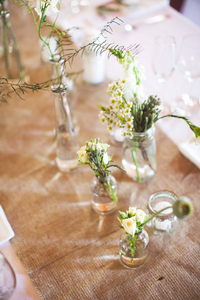 Burlap table runner. Single stem greens in mix and match bottles. Wedding reception decor. Green White Rustic South African Wedding // Justin Davis Photography
