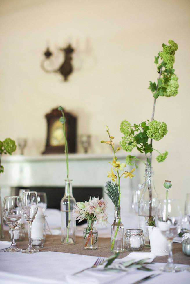 Single stem greens in mix and match bottles. Wedding reception decor. Green White Rustic South African Wedding // Justin Davis Photography