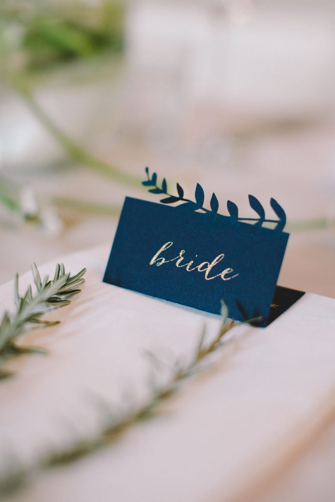 Navy blue bride and groom place cards with leaf patterning. 