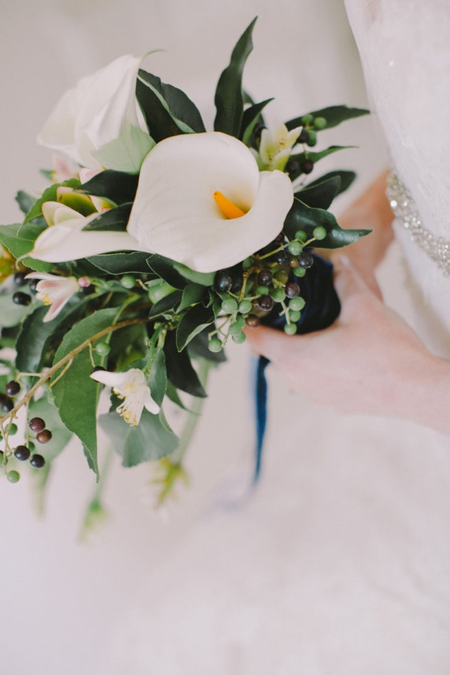 Green and white bridal bouquet with Calla Lily, greens and blue berries wrapped in navy ribbon