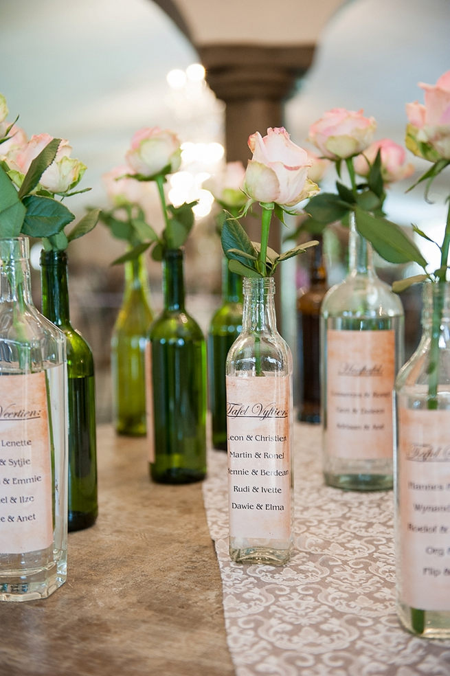 DIY Seating Chart: Vintage bottles holding single stem roses were wrapped in home printed labels and displayed on a table. Blush Pink and Powder Blue Spring Wedding // D’amor Photography