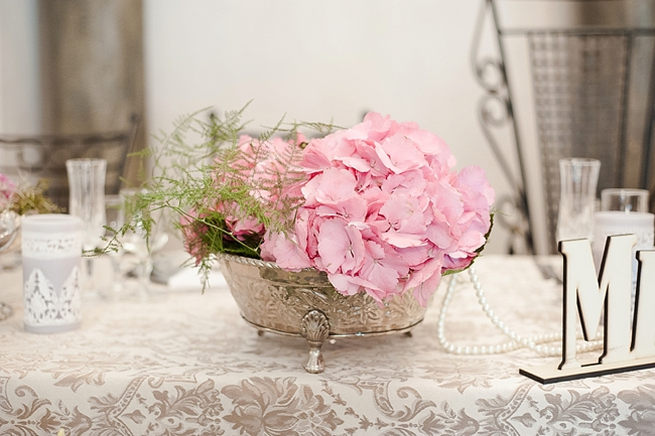 Romantic floral arrangement: silver urn with pink hydrangea and leather leaf ferns place on bridal table.