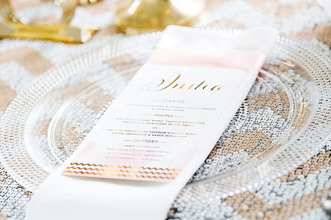 Gold embossed script style menu, clear beaded underplate with white and gold glitter chevron table linen