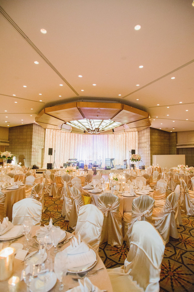 Chic Wedding reception florals of white hydrangea, blush roses, white roses and green fillers with white blossoms.  Clear glass vases with floating candles and silver votives.