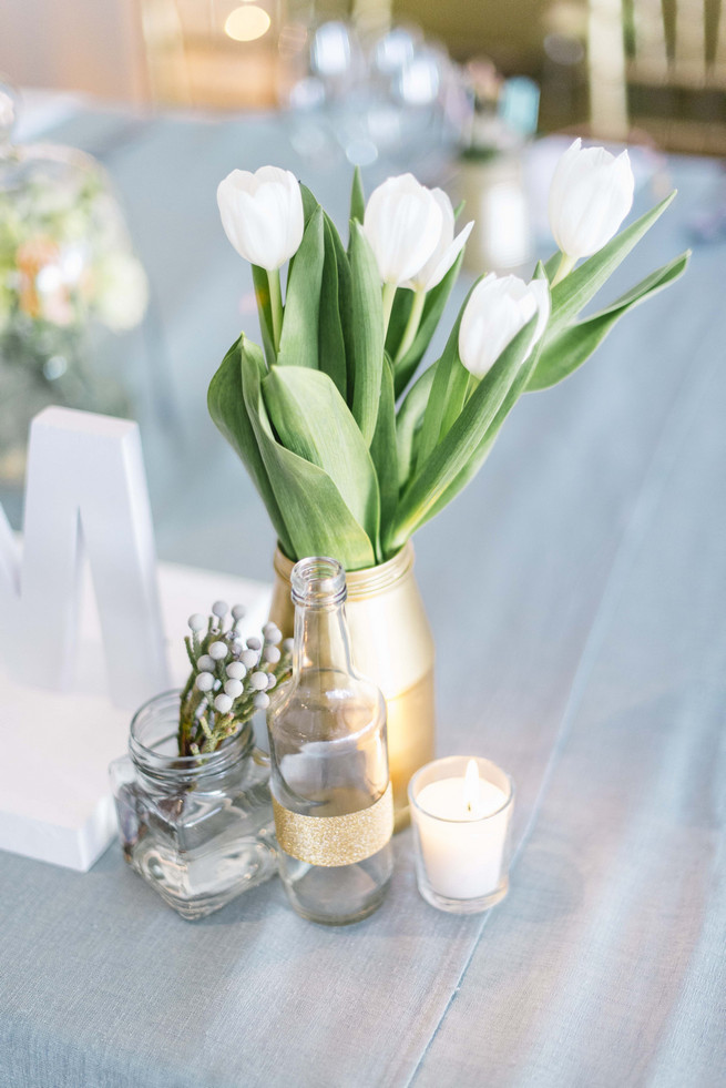 Gold painted bottles on reception tables with white tulips. White and Gold DIY Chevron Wedding, South Africa, by Claire Thomson Photography