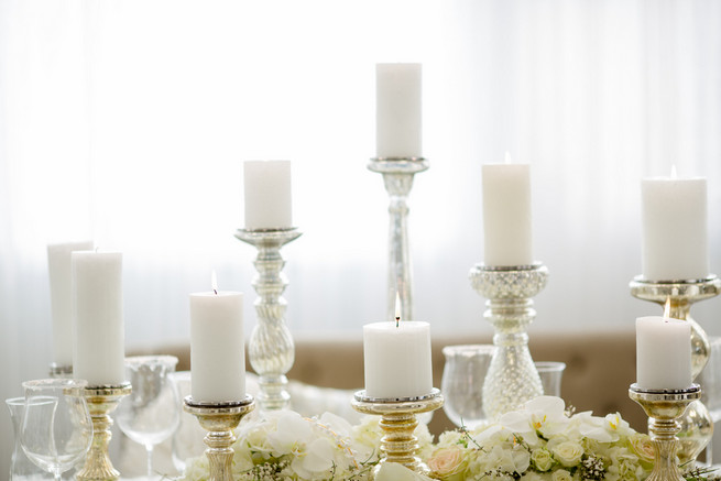 Gorgeous pillar candles. Super chic sweetheart table! White on White Glamorous Wedding Ideas by ENV Photography. Styled by Elegant Touches and Atmosphere Weddings