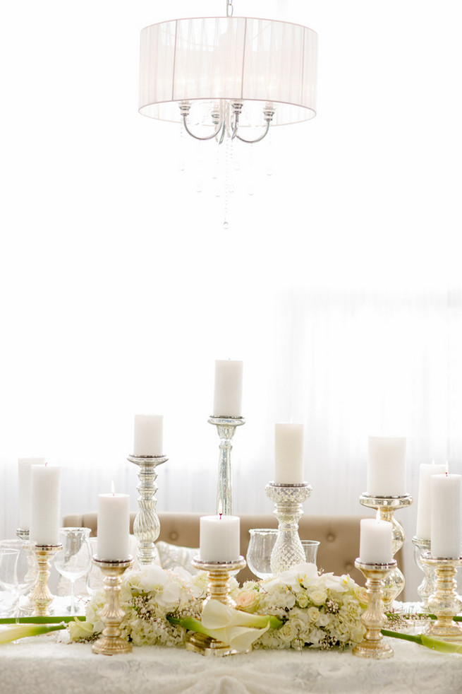 Gorgeous pillar candles. Super chic sweetheart table! White on White Glamorous Wedding Ideas by ENV Photography. Styled by Elegant Touches and Atmosphere Weddings