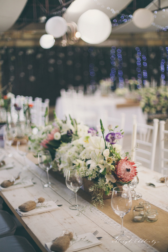 Farm style blooms. Rustic table decor with wood slabs, vintage bottles, lace and single stem roses.