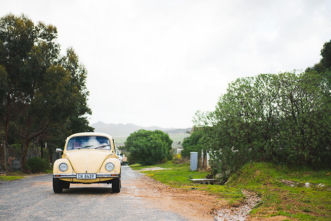 Bride arriving in vintage Volkswagen Beetle. Woodlands Winter Wedding in deep blue, burgundy and emerald green // Knit Together Photography