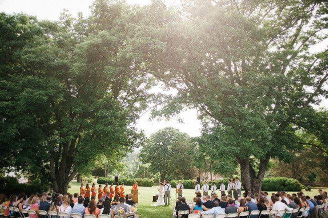 Outdoor wedding ceremony under trees.  Coral Navy Mustard Wedding / Meredith McKee Photography