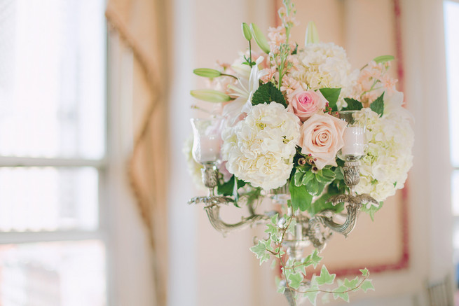 White hydrangea, cream and blush roses, white lillies, ivy wedding floral centerpiece