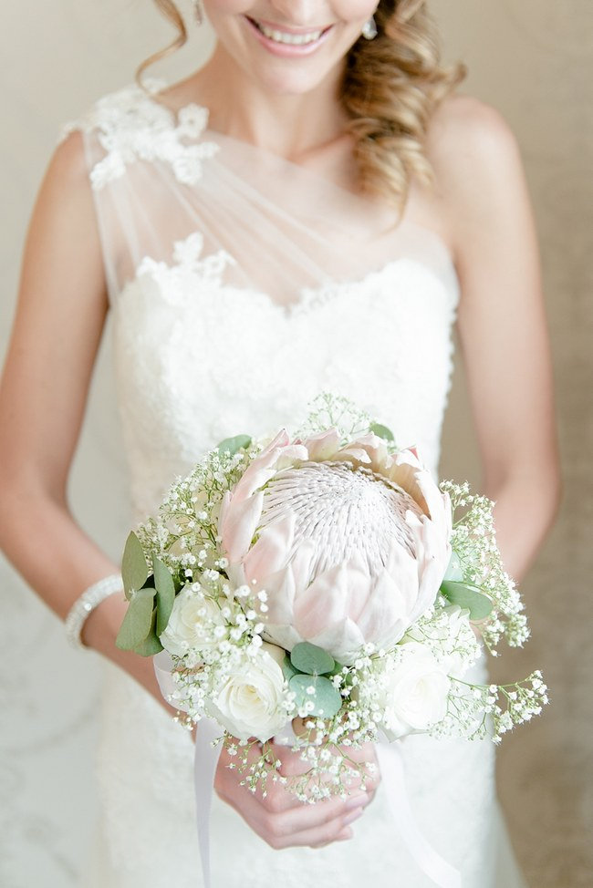 Breathtaking Wedding Bouquet Recipe: Simple but striking - a large blush pink King Protea surrounded by delicate babys breath, eucalyptus and white roses. Click to blog for more gorgeous bouquet ideas. 