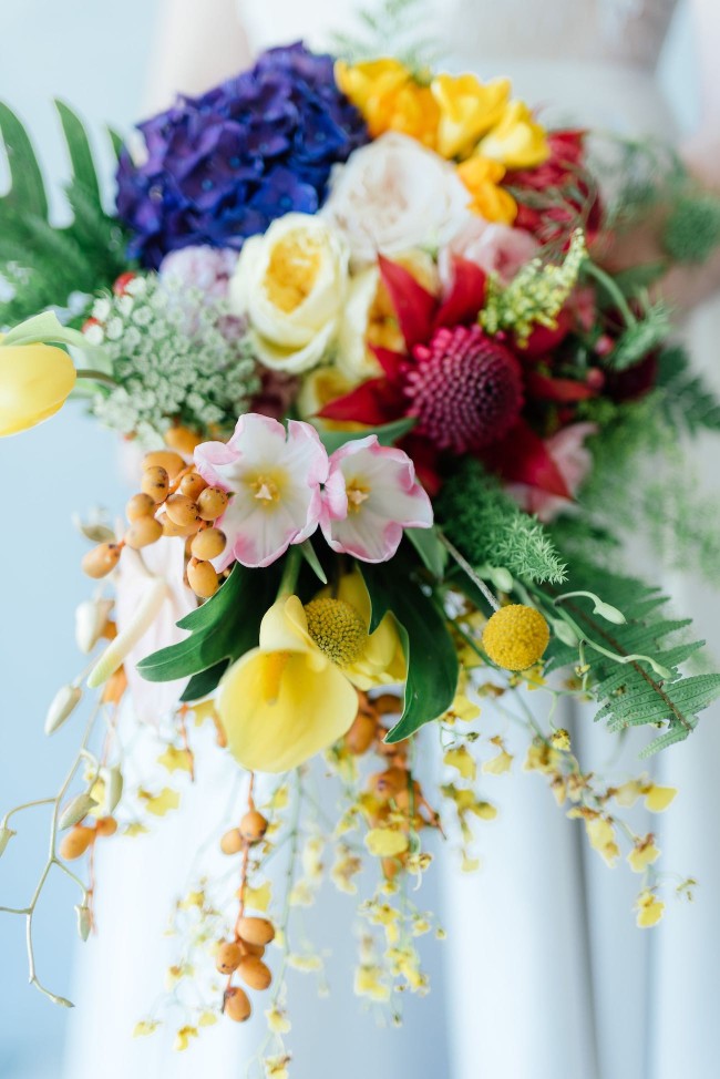 STUNNING tropical wedding bouquet made from a cascade of bright blue hydrangea, yellow lilies, ferns, tulips. roses, queen annes lace, billies balls, protea and beautiful blooms! Super cute "tutti frutti", Carmen Miranda style tropical flower crown for a tropical bride in bright colors. Fun and cute. Tropical Wedding Ideas photographed by Debbie Lourens Photography